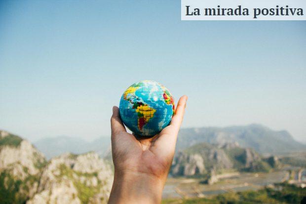 Person Holding World Globe Facing Mountain