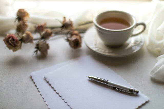 Taza de té junto a una carta y un bolígrafo sobre la mesa