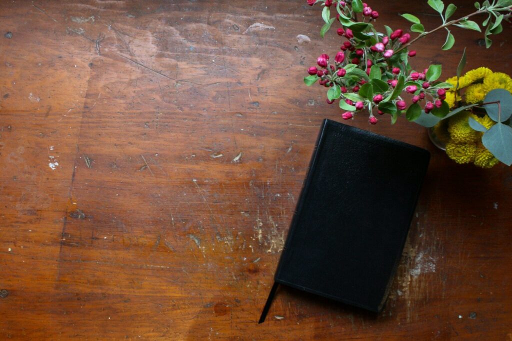 Cuaderno cerrado con flores sobre una mesa de madera para escribir frases positivas